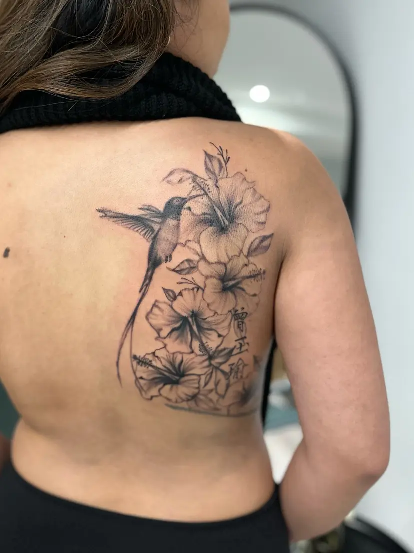 Hibiscus flowers and hummingbird tattoo on the upper back