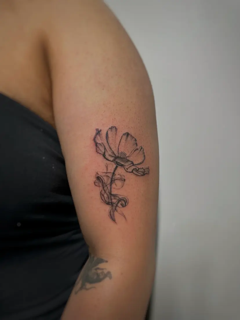 Fine-line poppy tattoo on the back of an arm