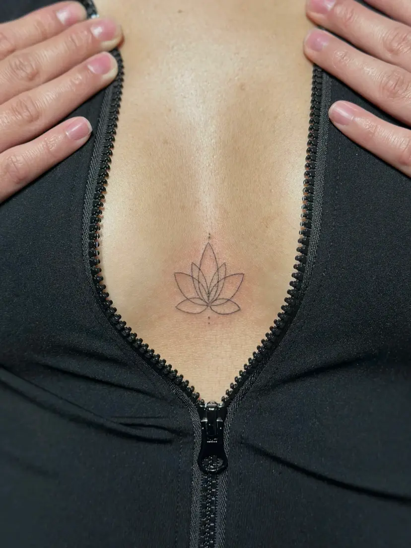 Fine-line lotus tattoo on the sternum