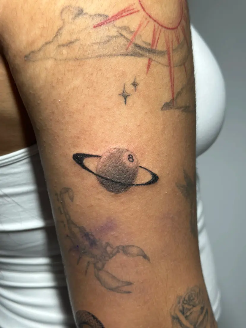Eight-ball planet tattoo with sparkles on an upper arm
